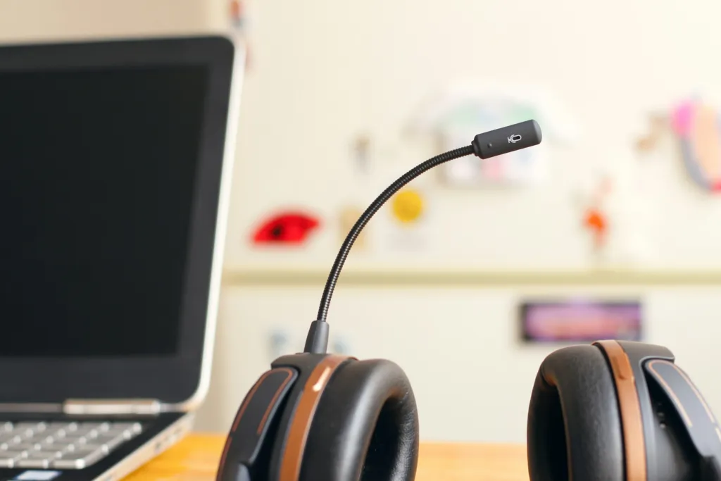 Headset bredvid en bärbar dator på ett skrivbord